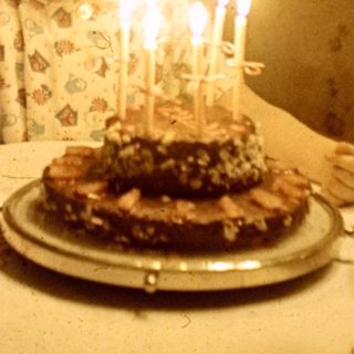 Child sits at a table with a birthday cake.