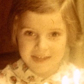 Child sits at a table with a birthday cake.
