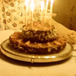 Child sits at a table with a birthday cake.