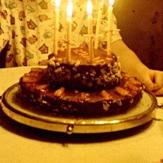 Child sits at a table with a birthday cake.