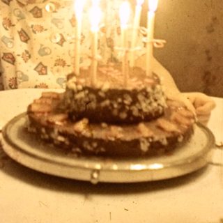 Child with birthday cake and candles at a table.