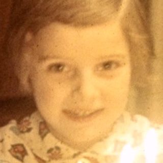 Child with birthday cake and candles at a table.