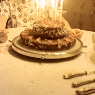 Child with birthday cake and candles at a table.