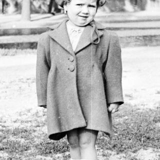 Black and white image of a young girl in a coat.