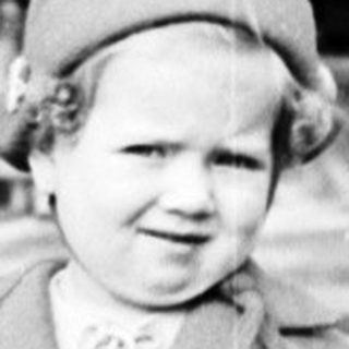Black and white image of a young girl in a coat.