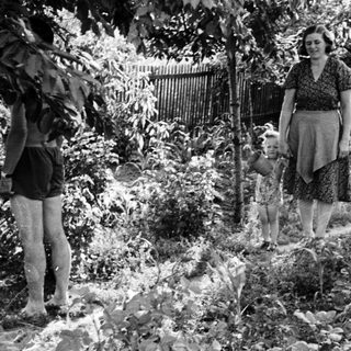 Woman and child stroll through a garden scene.