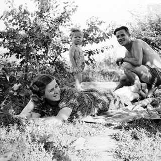 Family enjoying time outdoors in a grassy, shaded area.