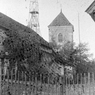 Old building with a tower and fence in background.