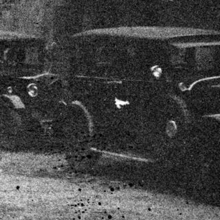 People and cars on a street, vintage black and white photo.