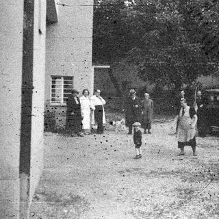 People and cars on a street, vintage black and white photo.