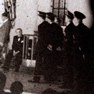 Group of people on stage with flags and a ladder.