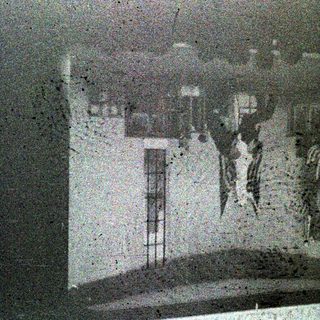 Here's a brief summary of the image: Grainy, indistinct interior scene with a window and figures.