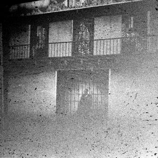 Gritty, grainy image of a window with a blurred interior.