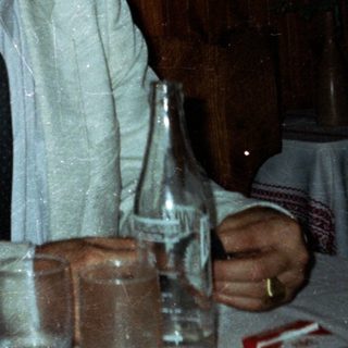 People at a table; one smokes, others drink.