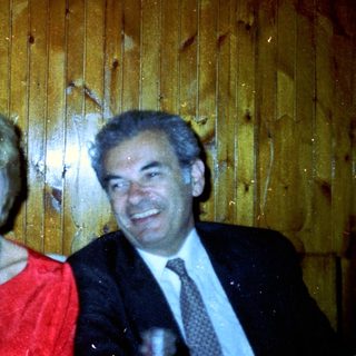 Three people pose for a photo against a wooden wall.