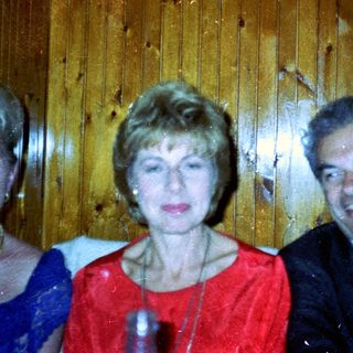 Three people pose for a photo against a wooden wall.