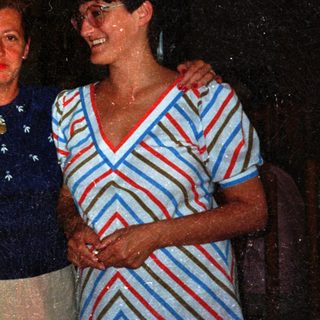 Four people standing together, smiling, in a dimly lit setting.