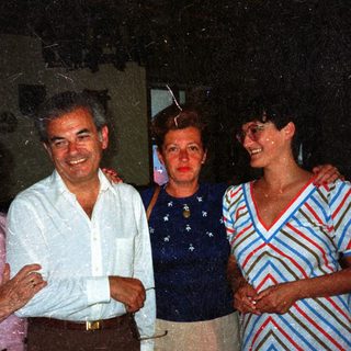 Four people standing together, smiling, in a dimly lit setting.