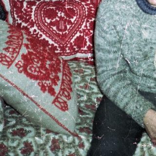 Man seated on a patterned couch in a vintage room.