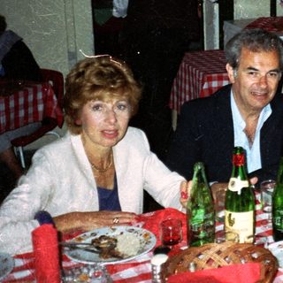 Three people dine at a table with food and drinks.