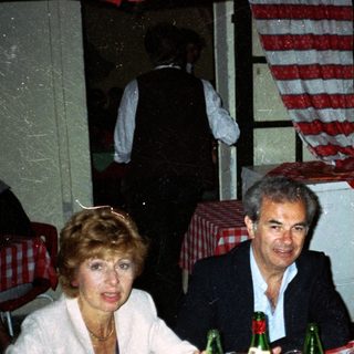 Three people dine at a table with food and drinks.
