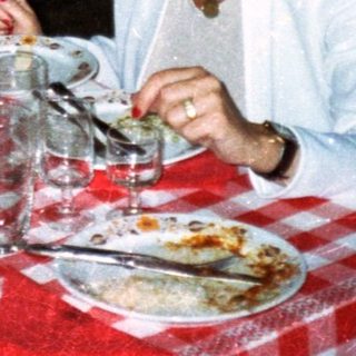 Three people dine at a table with food and drinks.