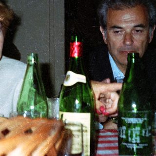 Couple seated at table with drinks, looking concerned.