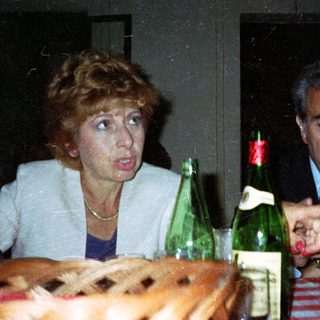 Couple seated at table with drinks, looking concerned.