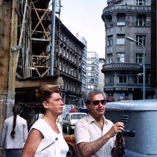 Couple walks down a street with building construction nearby.