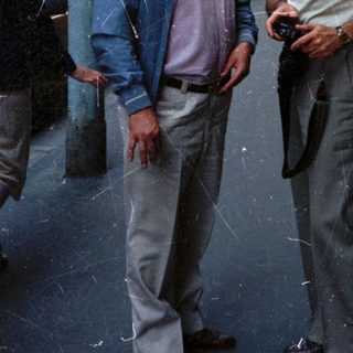 Two men in sunglasses stand on a city street.