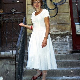 Woman stands on stairs, in front of a building.