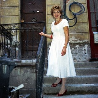 Woman stands on stairs, in front of a building.