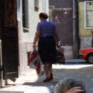Man takes a photo in a narrow, cobbled alleyway.