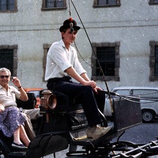 Woman and driver in a horse-drawn carriage.
