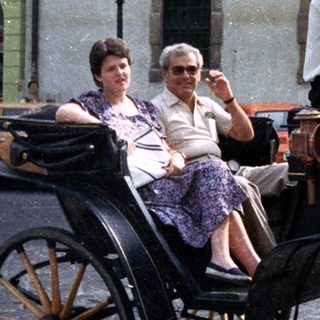 Woman and driver in a horse-drawn carriage.