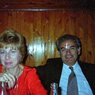 Couple seated together, smiling, in a wood-paneled setting.