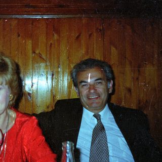 Couple seated together, smiling, in a wood-paneled setting.