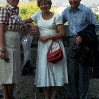 Three people pose with a cityscape view in the background.