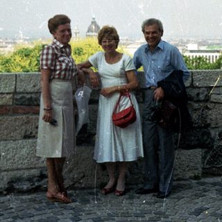 Three people pose with a cityscape view in the background.