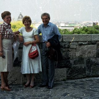 Three people pose with a cityscape view in the background.