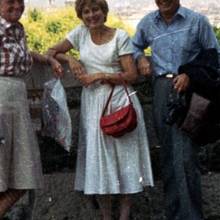 Three people pose with a cityscape view in the background.