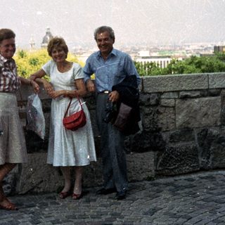 Three people pose with a cityscape view in the background.