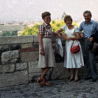 Three people pose with a cityscape view in the background.