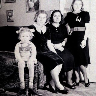Three women and a child pose indoors, vintage clothing.