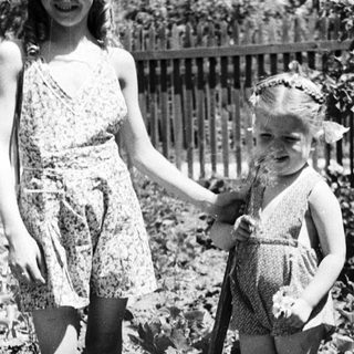 Two young girls standing outside, holding hands.