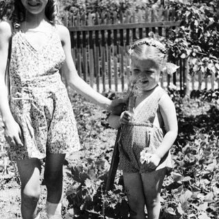 Two young girls standing outside, holding hands.