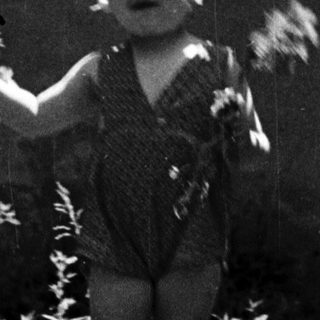 Child playing outdoors, surrounded by foliage and greenery.