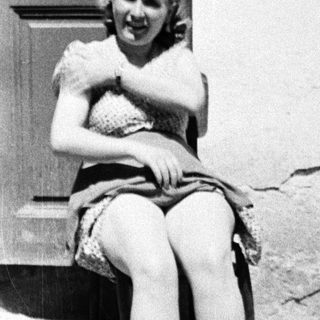 Woman sits, soaking feet in a bowl outdoors.
