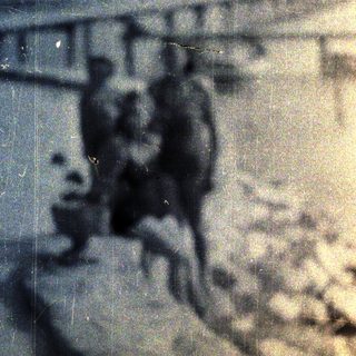 Here's a brief summary: Shadowy figures and landscape in a distressed, aged photograph.