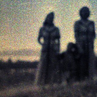 Faint figures stand silhouetted against a blurry, hazy landscape.
